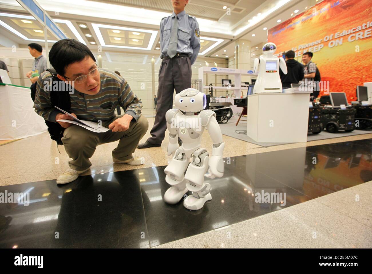 A man looks at a demonstration of a prototype of the humanoid robot "Nao"  during the 2011 IEEE International Conference on Robotics and Automation  (ICRA 2011) in Shanghai May 11, 2011. The