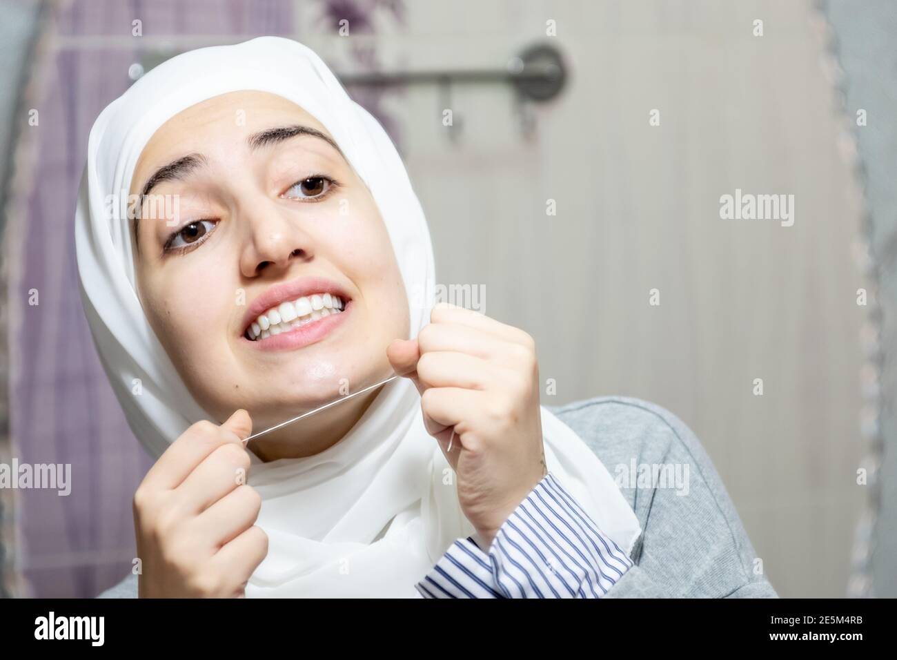 Arabic muslim woman cleaning her teeth with dental floss Stock Photo ...