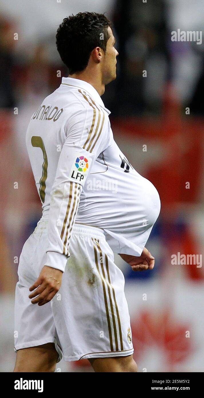 Real Madrid's Cristiano Ronaldo holds a ball in his jersey as he celebrates  completing a hat-trick at the end of their Spanish first division soccer  match against city rivals Atletico Madrid at