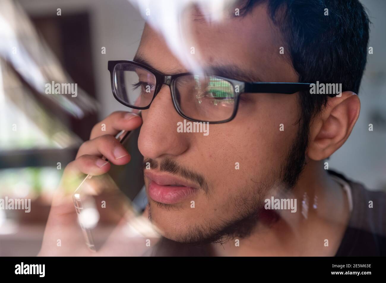 Guy talking on the phone while looking from window glass Stock Photo