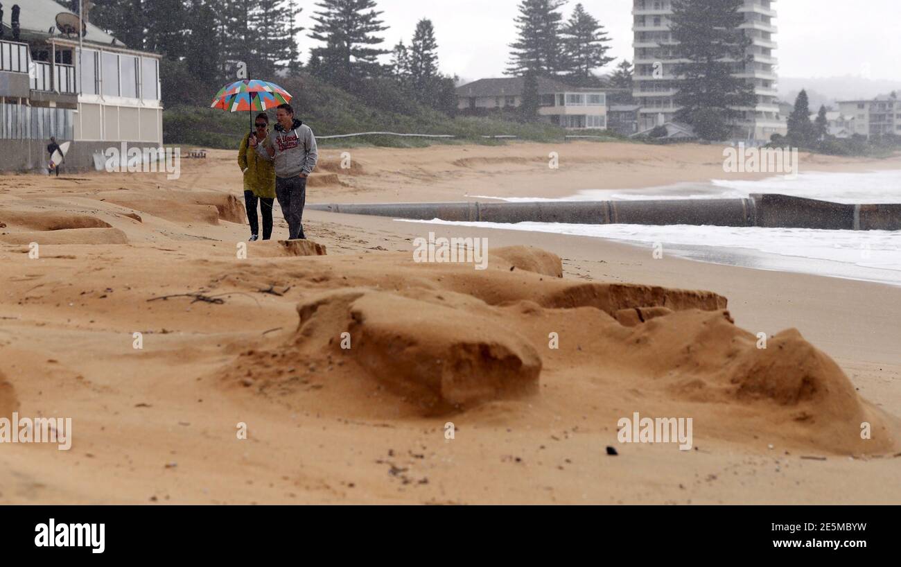 A couple walks along Sydney's Collaroy Beach after a heavy storm eroded the sand, April 22, 2015. A cyclonic storm lashed Australia's east coast for a third day on Wednesday, causing millions of dollars of damage to property and infrastructure in Sydney and other cities.   REUTERS/Jason Reed Stock Photo