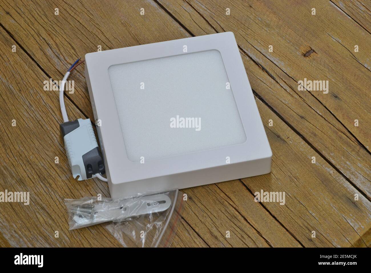 White overlay led ceiling light with wires and accessories for mounting on an aged wooden background Stock Photo