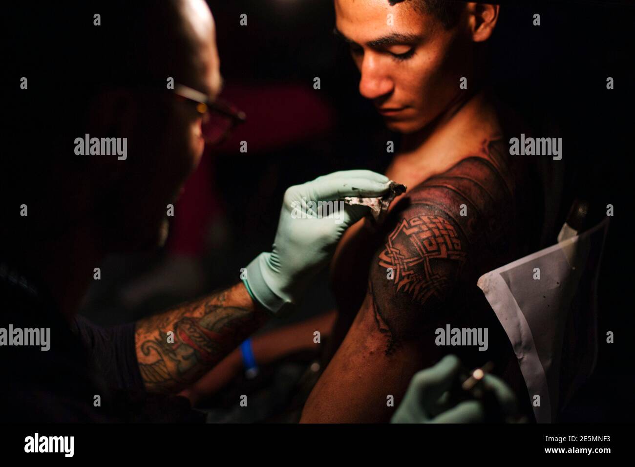 A tattoo artist works on the image of a skull and roman armor on the back  of a man at the New York City Tattoo Convention in New York May 17, 2013.