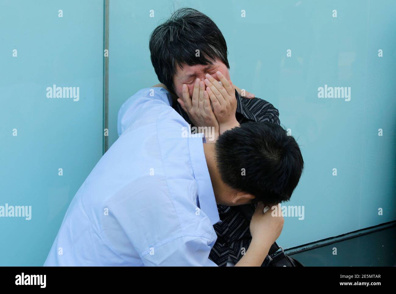 A woman, whose son was aboard the missing Malaysia Airlines flight MH370, cries with her husband after they failed to express their appeals to the airline outside its office in Beijing June 11, 2014. Months of searches have failed to turn up any trace of the missing Boeing 777, which disappeared on March 8 carrying 239 passengers and crew shortly after taking off from Kuala Lumpur bound for Beijing. REUTERS/Jason Lee (CHINA - Tags: TRANSPORT DISASTER) Stock Photo