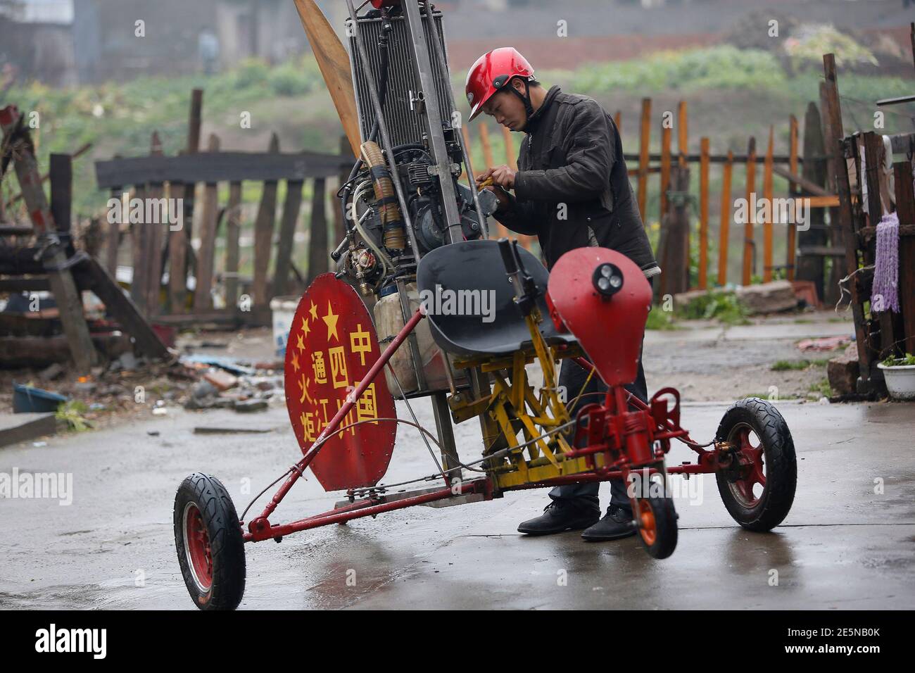 Luo Jinsha checks his home-made aircraft during a test flight on the outskirts of Shanghai, February 26, 2014. Luo, 28, a migrant worker living in Shanghai, spent around eight months and 40,000 yuan ($6,529) to build the plane to fulfil his dream to fly. Despite failing during the first test flight, Luo said he will not give up hope on improving his plane so as to eventually fly it successfully. The aircraft was able to move quickly on the ground but could not take to the air on second attempt. REUTERS/Aly Song (CHINA - Tags: SOCIETY TRANSPORT) Stock Photo