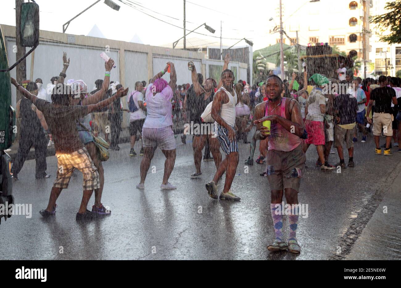A reveller protects his drink as it rains during Jouvert, part of Carnival  in Saint James, Port of Spain February 16, 2015. Jouvert originates from  the French phrase "jour ouvert", meaning daybreak