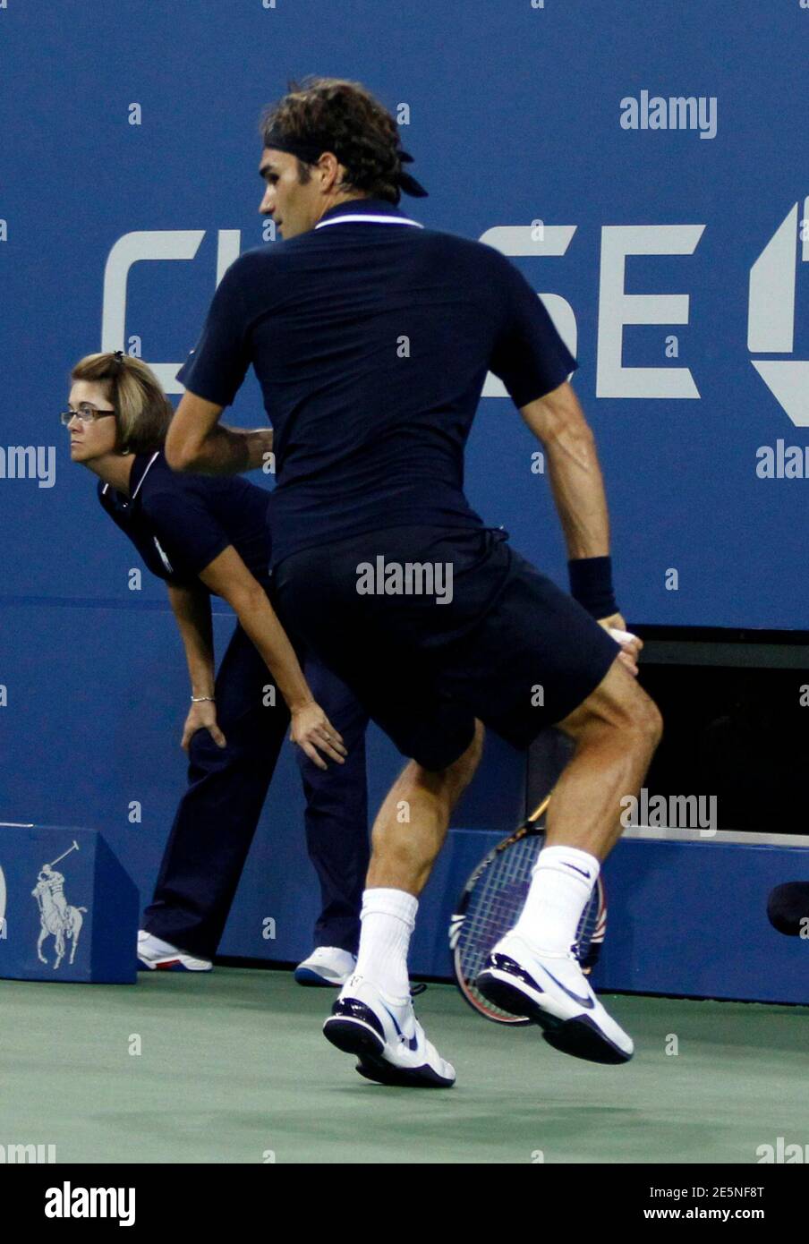 Roger Federer of Switzerland returns a winning shot between his legs while  playing Brian Dabul of Argentina during their opening night match at the  U.S. Open tennis tournament in New York, August