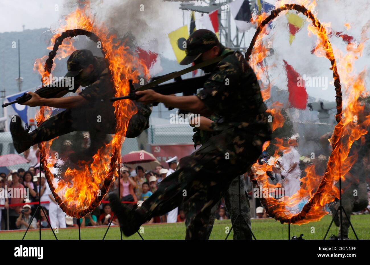 Chinese People's Liberation Army (PLA) soldiers jump through rings of fire in a war game as part of the show for the public during an open day at the Ngong Shuen Chau Naval Base on Hong Kong's Stonecutters Island July 28, 2012. The naval base was open to the public on Saturday, four days ahead of the PLA Army Day on August 1. REUTERS/Tyrone Siu (CHINA - Tags: POLITICS MILITARY) Stock Photo