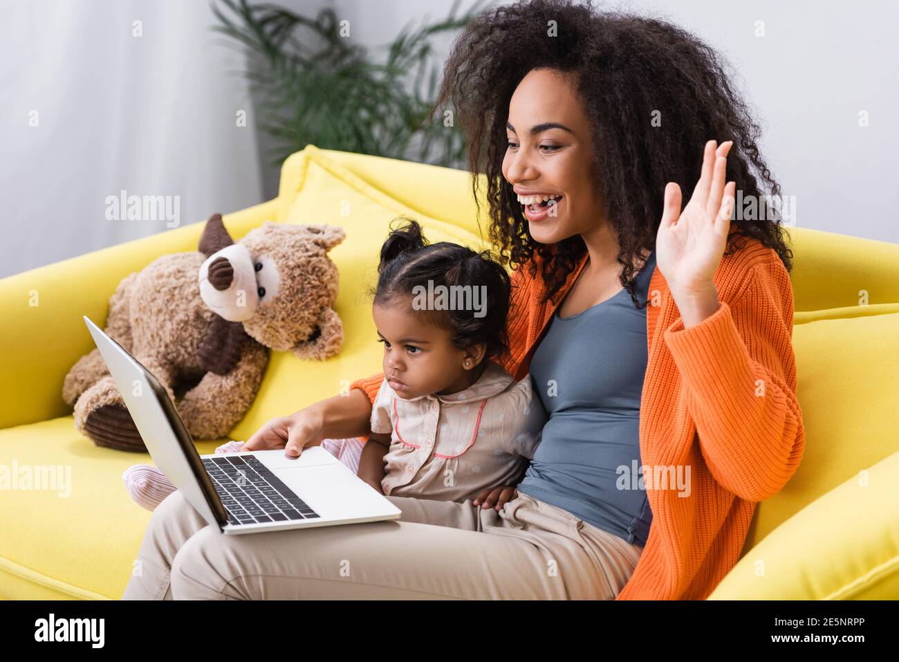 happy african american mother waving hand during video call near ...