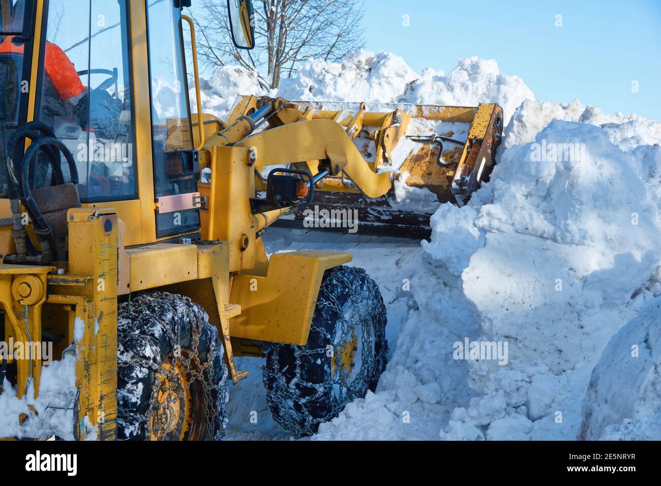 Snow plow truck with snow chains in the wheels in action, plowing snow
