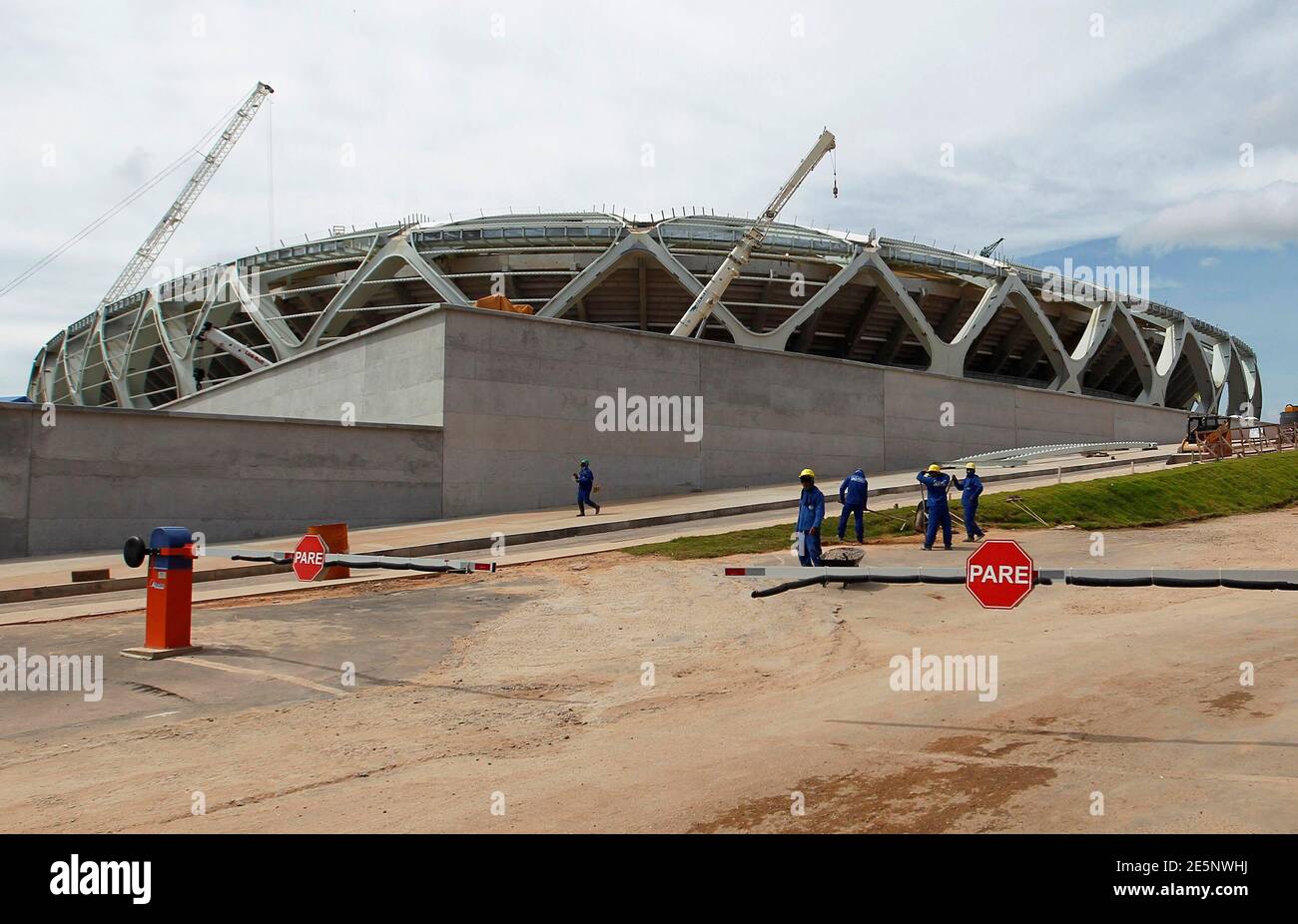 Workers stand outside the Arena Amazonia stadium under construction to host several 2014 World Cup soccer games, in Manaus December 14, 2013. Construction worker Marcleudo de Melo Ferreira fell to his death from the roof earlier in the day after a cable broke, adding to safety concerns as the country races to finish building in time to host the 2014 World Cup of soccer. REUTERS/Bruno Kelly (BRAZIL - Tags: SPORT SOCCER WORLD CUP DISASTER BUSINESS CONSTRUCTION) Stock Photo