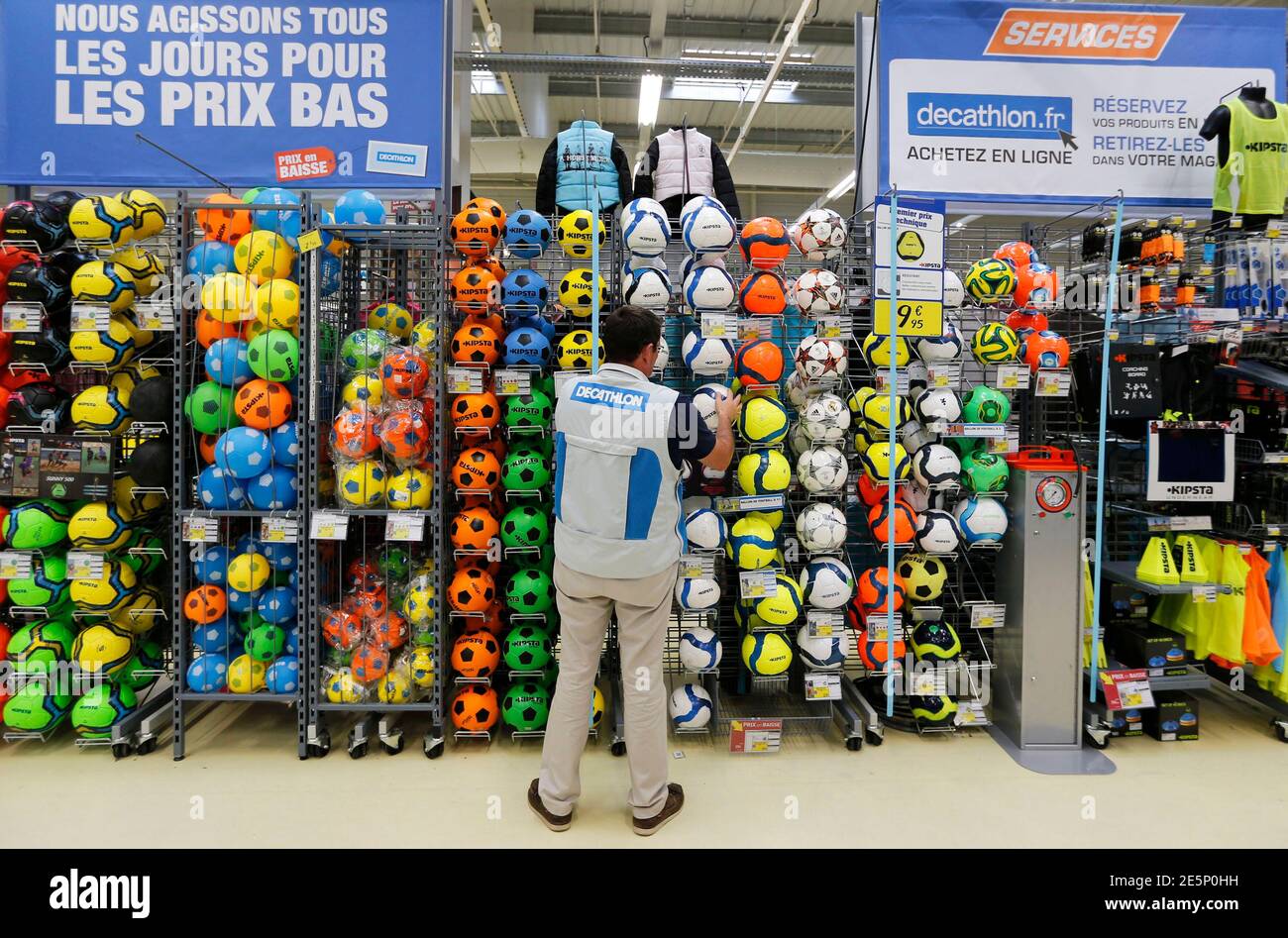 An employee installs soccer balls in an aisle at the French sports  equipment and sportswear company Decathlon store in Merignac near Bordeaux  July 10, 2014. The group, number one in French distribution