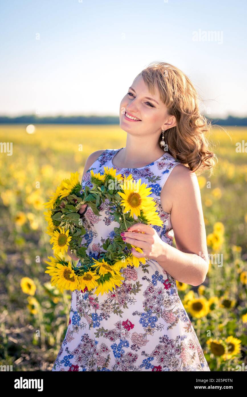 Cute redhaired smiling girl in the field full of sunflowers, wreath of ...