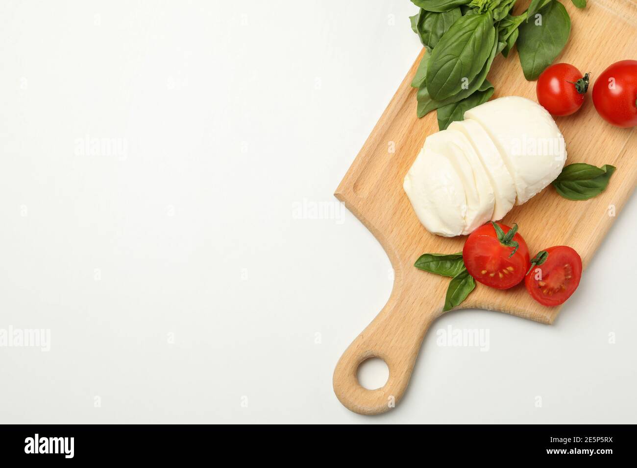 Board with mozzarella cheese, tomato and basil on white background Stock Photo