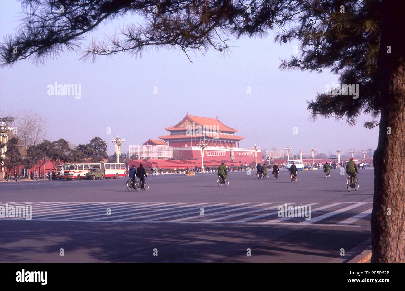 China 1986 cyclists pedal past the Gate of Heavenly Peace where Chairman Mao's portrait looks over Tiananmen Square. Stock Photo