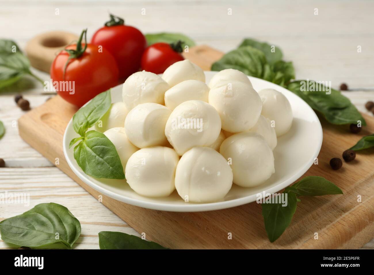 Concept of tasty eating with bowl of mozzarella cheese on white wooden background Stock Photo