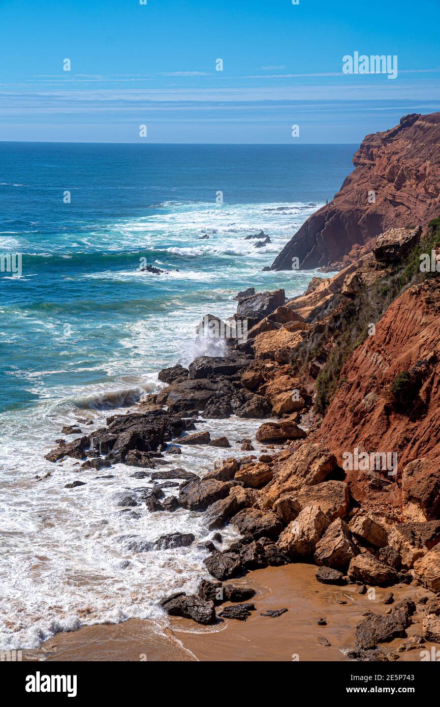 Red rocky cliffs with waves from the ocean, summer landscape perfect for holiday. Algarve region in Portugal, Europe. Stock Photo
