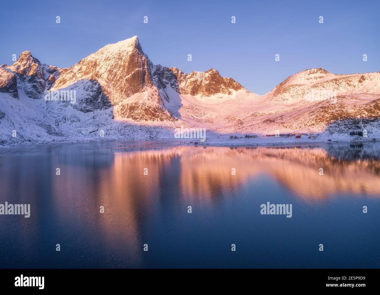 Snowy mountains and blue sky reflected in water at sunset Stock Photo