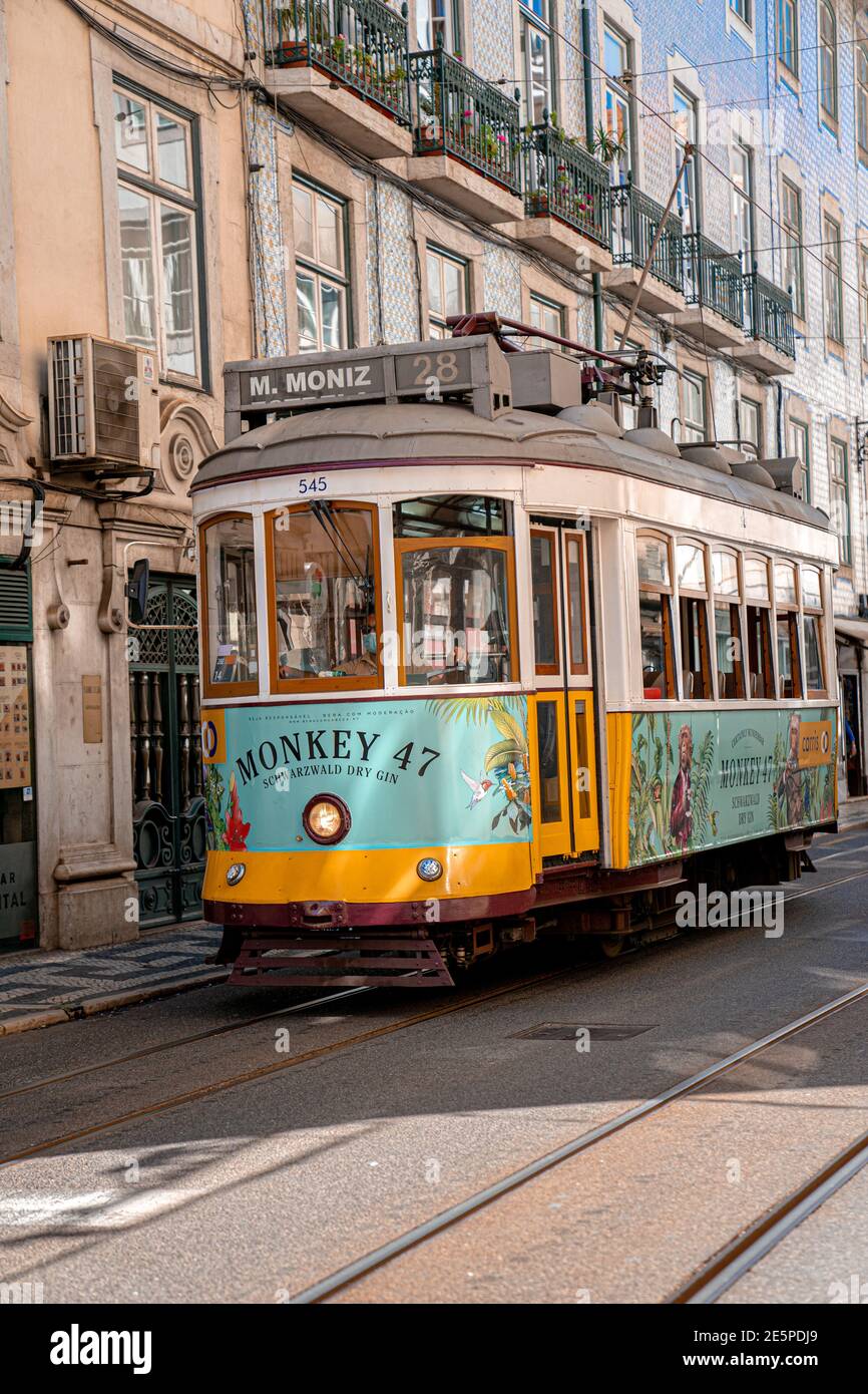 Lisbon - Portugal, August 2020: Unique yellow tram in the city downtown, public transportation in historic center with classic building. Stock Photo