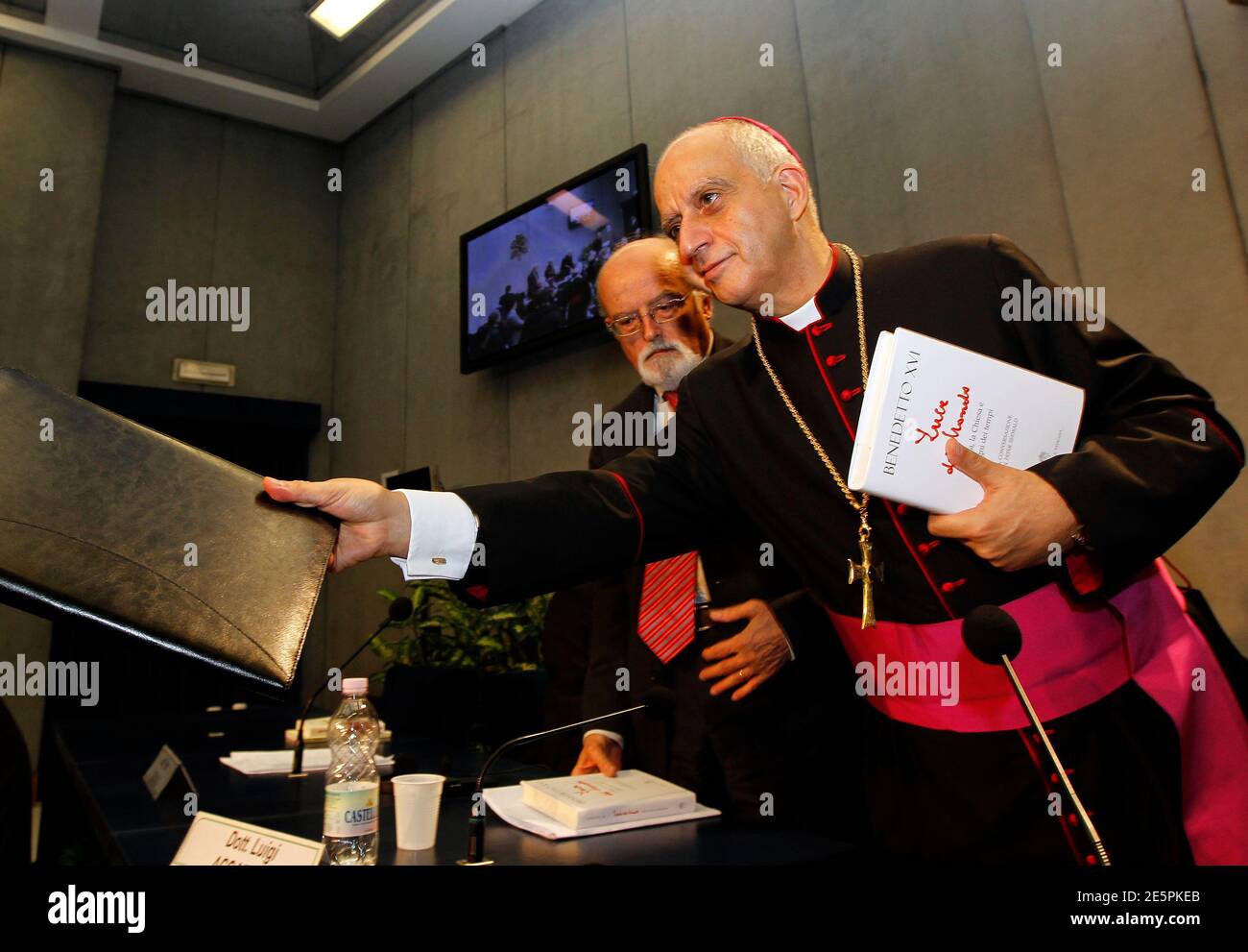 Archbishop Rino Fisichella (R) holds a new book about Pope Benedict XVI  as he leaves at the end of a news conference at the Vatican November 23, 2010. Pope Benedict says in the new book, called 'Light of the World: The Pope, the Church, and the Sign of the Times', that he would not hesitate to become the first pontiff to resign willingly in more than 700 years if he felt himself no longer able, 'physically, psychologically and spiritually', to lead the church. The book, an interview with German Catholic journalist Peter Seewald, has so far made headlines for the pope's cautious opening to the Stock Photo