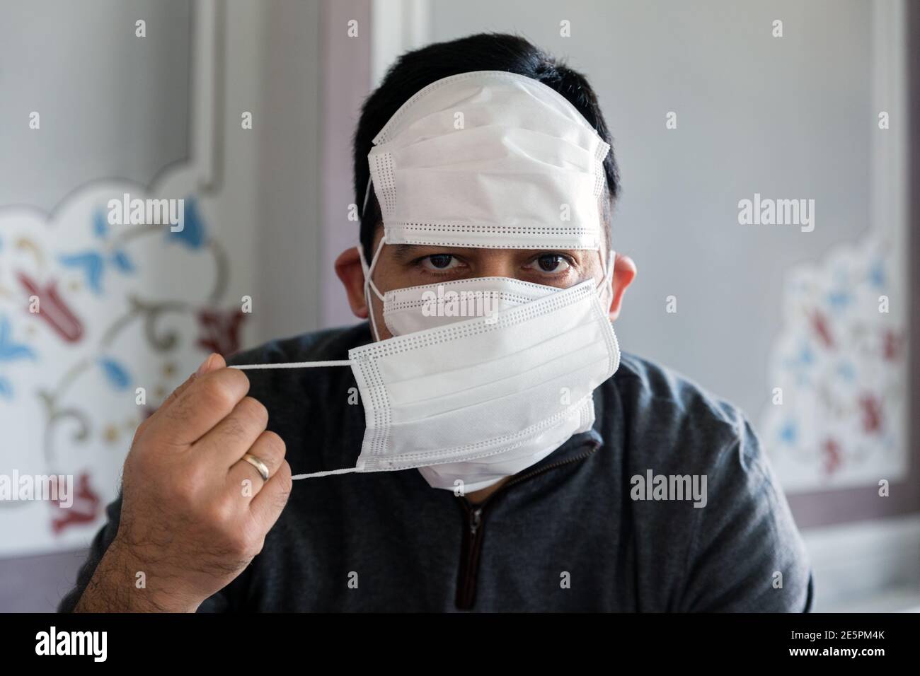 Interior shot front portrait of man with multiple masks, looking into lens Stock Photo
