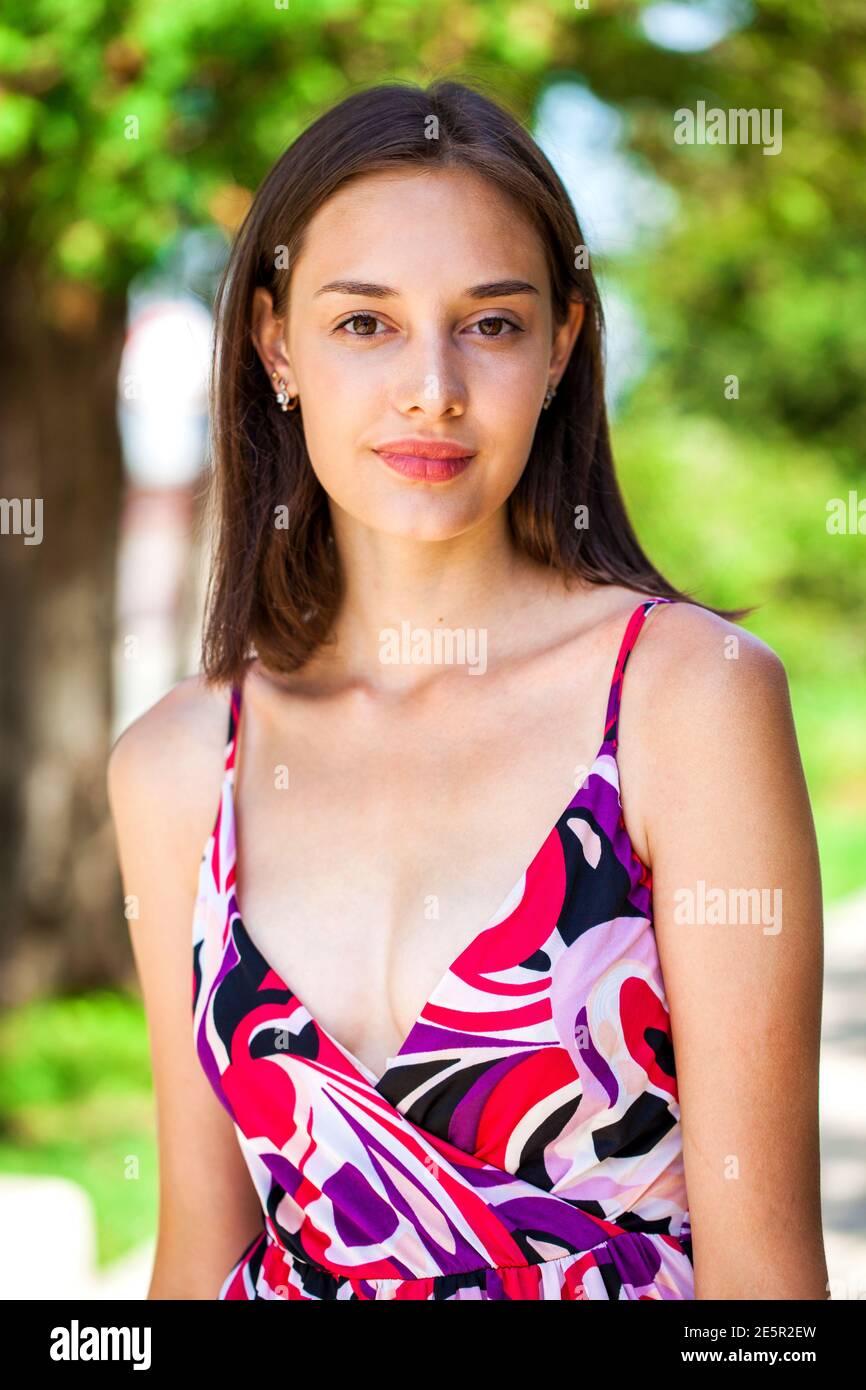 Portrait of a young beautiful brunette girl in dress posing in summer park  Stock Photo - Alamy