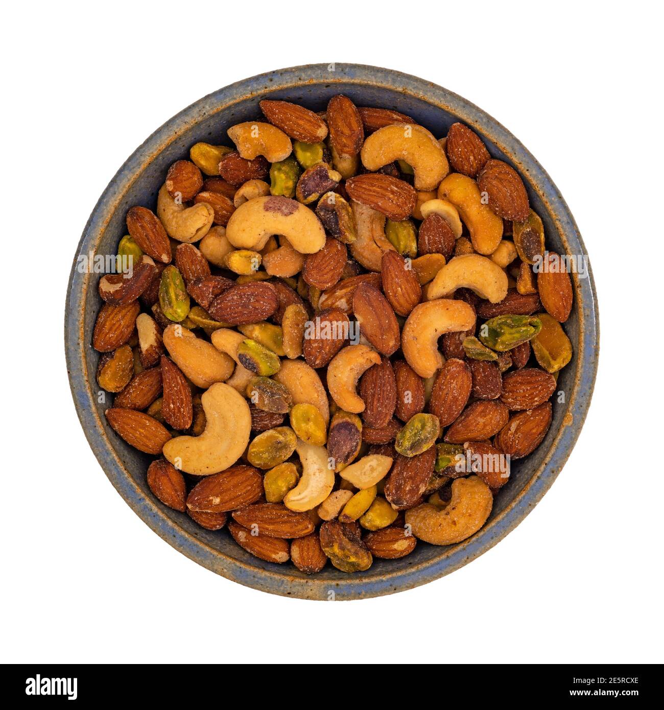 Top view of pistachio, almonds and cashews nuts in a stoneware bowl isolated on a white background. Stock Photo