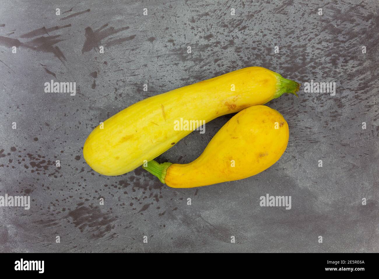 Top view of two home garden grown yellow summer squash on a gray mottled background. Stock Photo