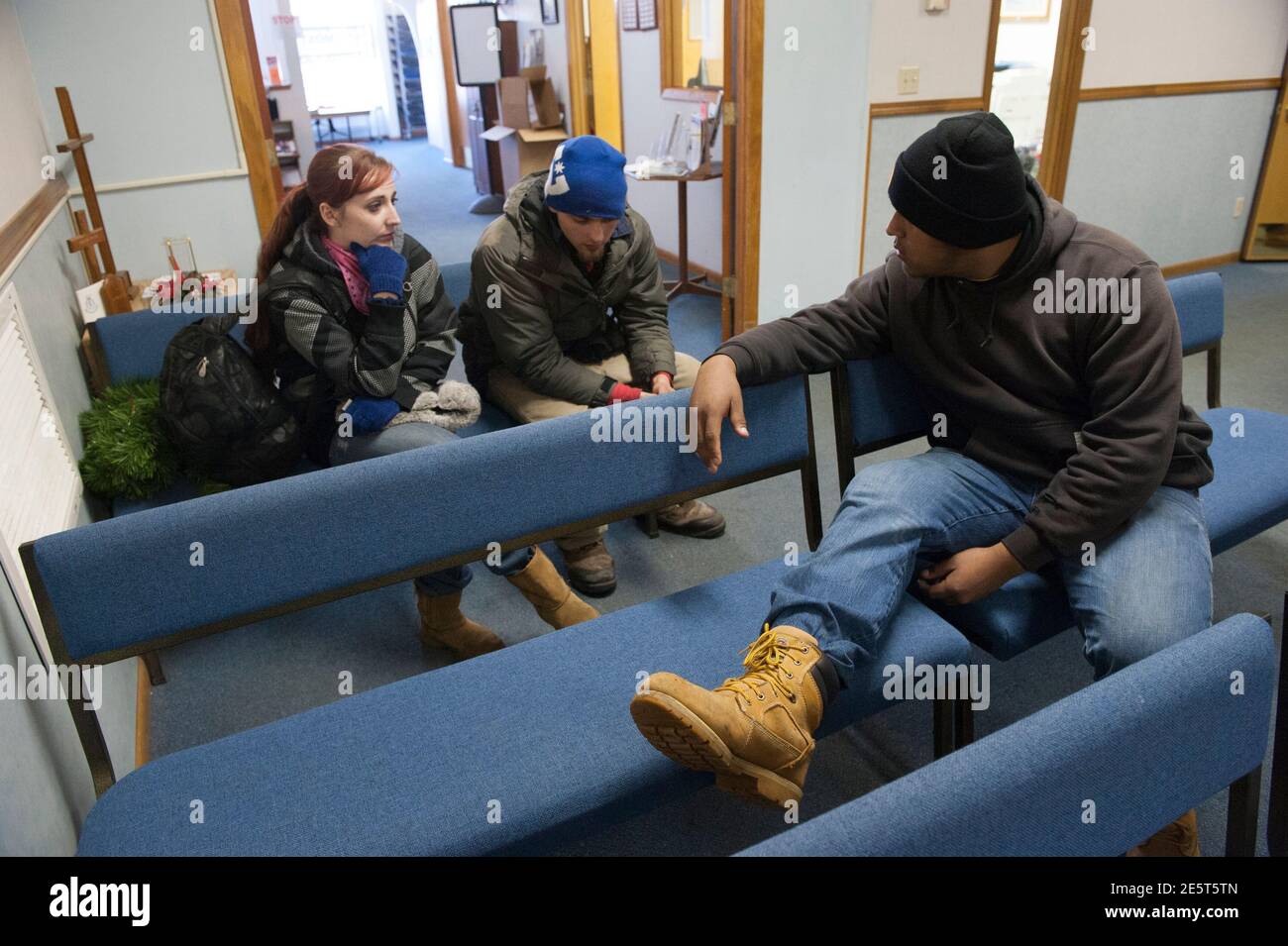 Terra Green (L), Jeff Williamson (C) and Bazileo Hernandez wait to talk to a social worker in hopes of getting help finding a place to stay for the night at the Salvation Army office in Williston, North Dakota on January 13, 2015. Like so many before them, Terra Green, Jeff Williamson and Bazileo Hernandez came to North Dakota's oil country seeking a better life. They just came too late. Itinerant, unskilled workers could as recently as last spring show up in the No. 2 U.S. oil producing state and vie for salaries north of $100,000 per year with guaranteed housing. The steep drop in oil prices Stock Photo