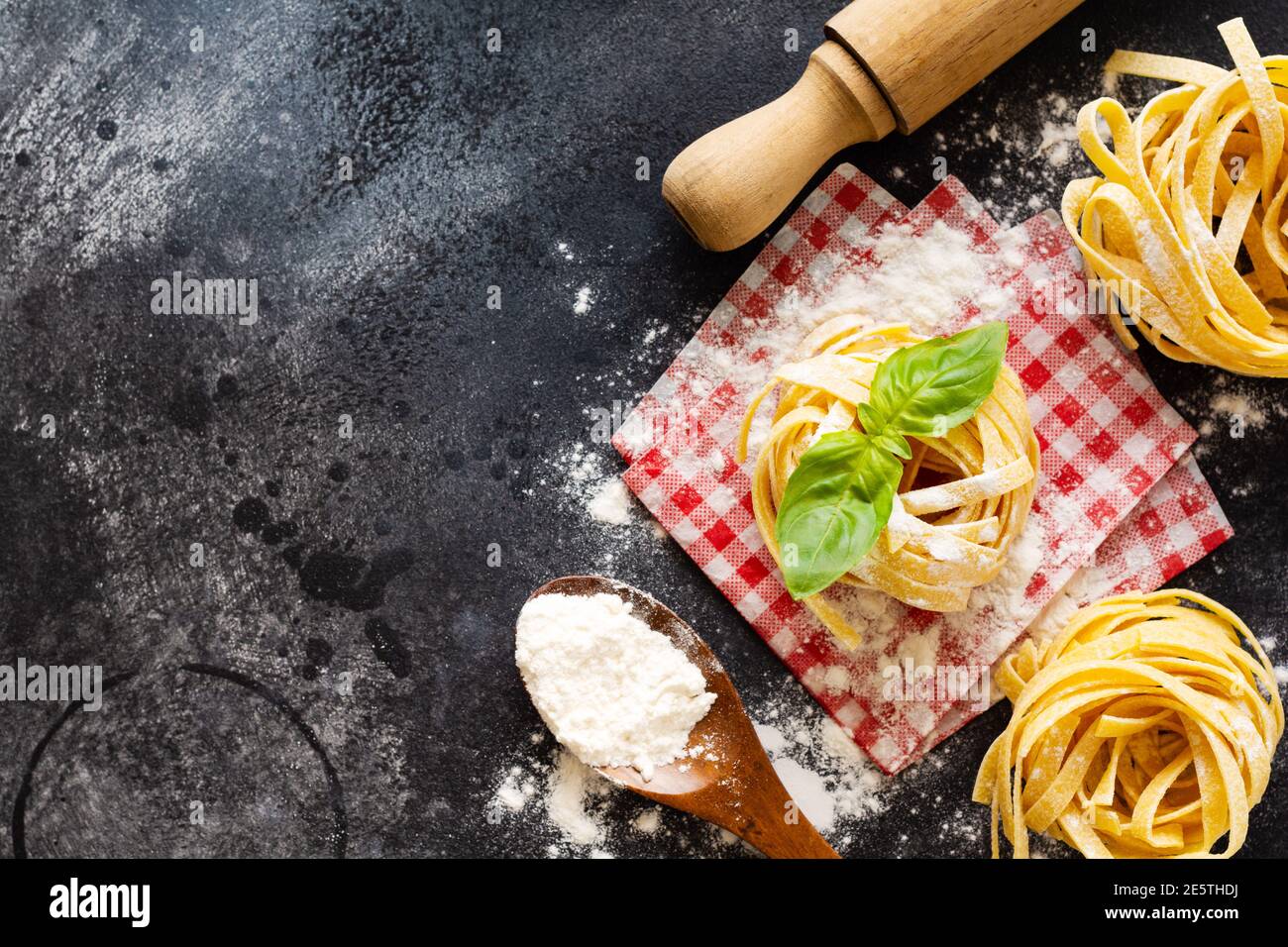 Cooking concept. Ingredients for traditional Italian homemade pasta tomatoes, raw egg, basil leaf on the dark concrete background table. Top view with Stock Photo