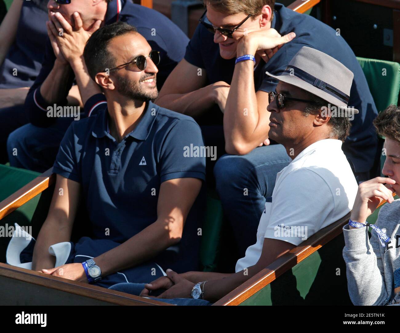 Former French professional tennis player Yannick Noah (R) watches the men's  singles match between Diego Schwartzman of Argentina and Gael Monfils of  France at the French Open tennis tournament at the Roland