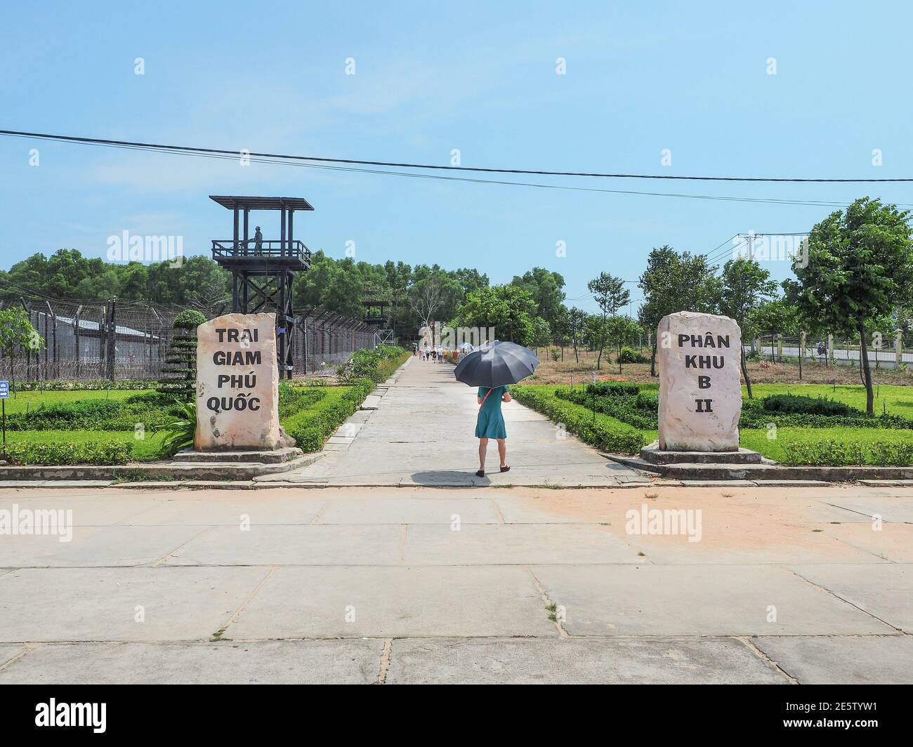 PHU QUOC, VIETNAM - March 27, 2017: Woman with black umbrella in the Entrance to Coconut Tree Prison with sign Trai Giam in Phu Quoc Island. Stock Photo