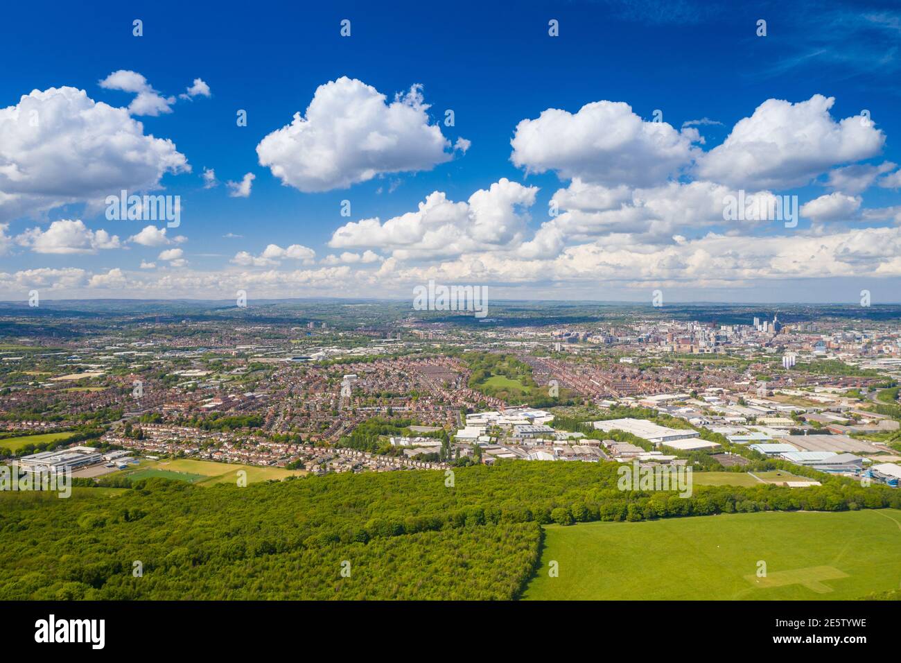 Aerial photo of the city of Leeds viewed from the village of Middleton and Middleton Park on a sunny day with white clouds in the sky and a lot of gre Stock Photo