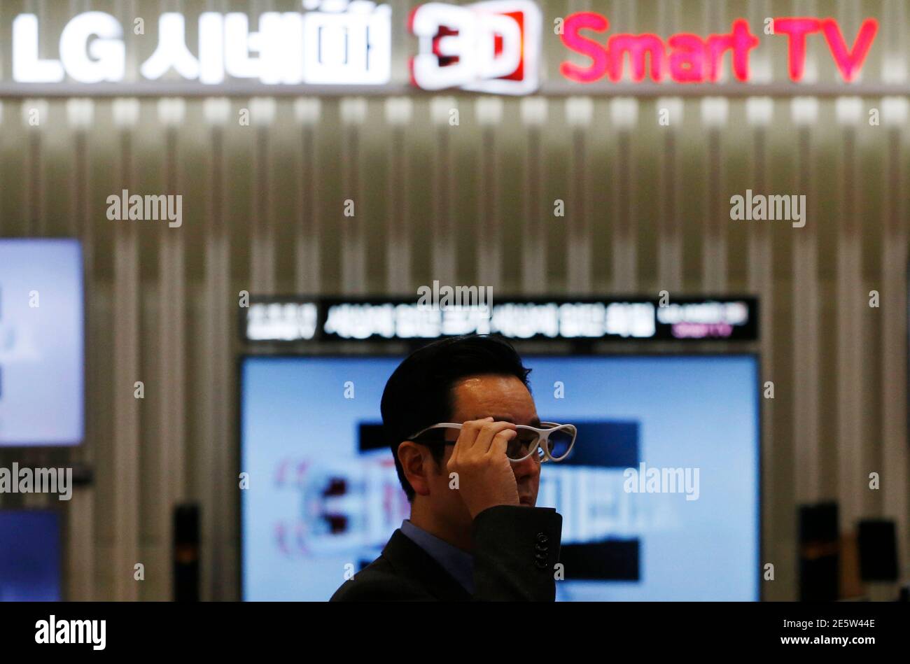 A customer wears a pair of 3D glasses in front of LG Electronics' 3D TV  sets at a store in Seoul January 23, 2014. LG Electronics Inc beat analyst  estimates by doubling