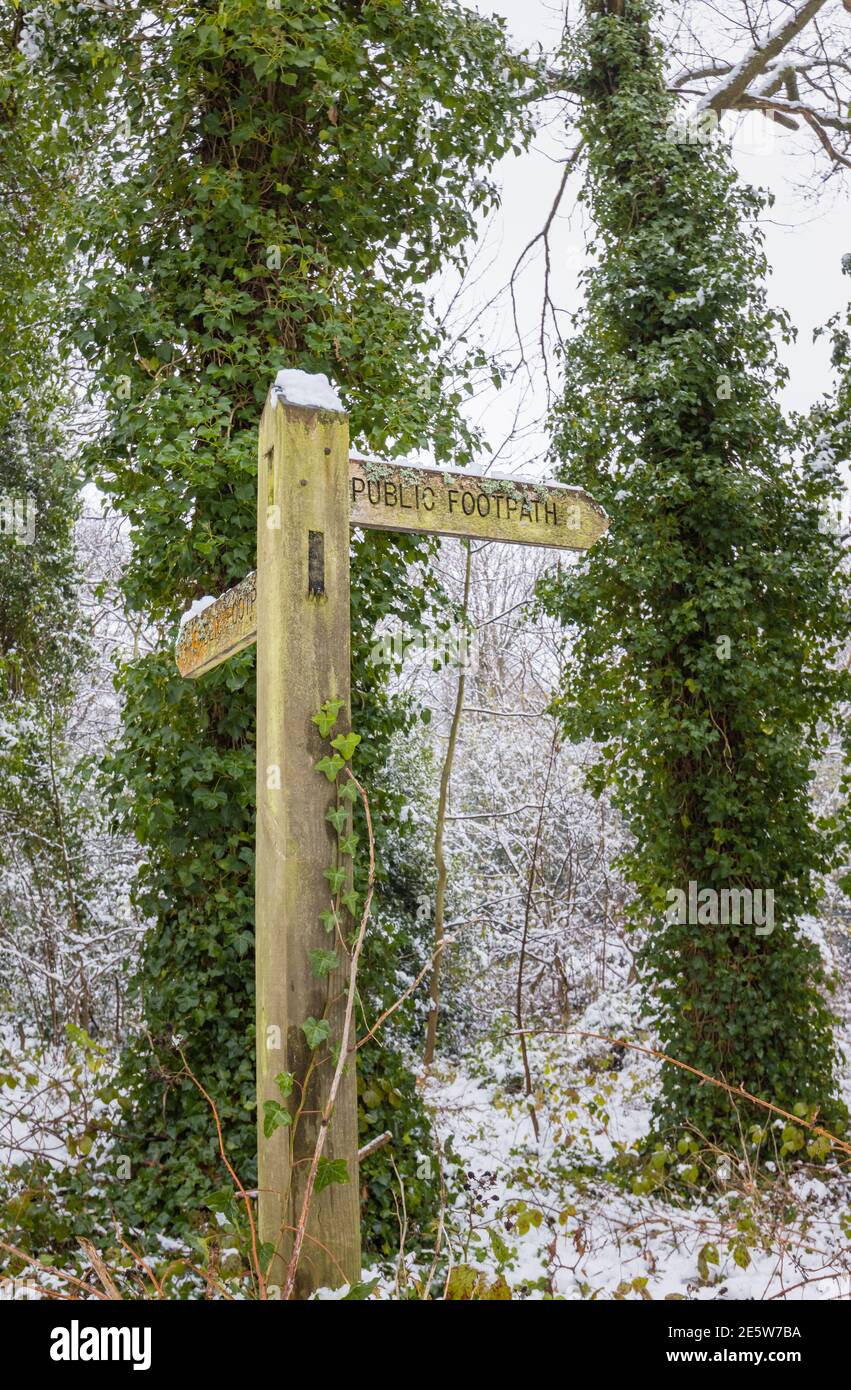 Wooden public footpath fingerpost signpost with snow after a heavy snowfall in Woking, Surrey, south-east England Stock Photo