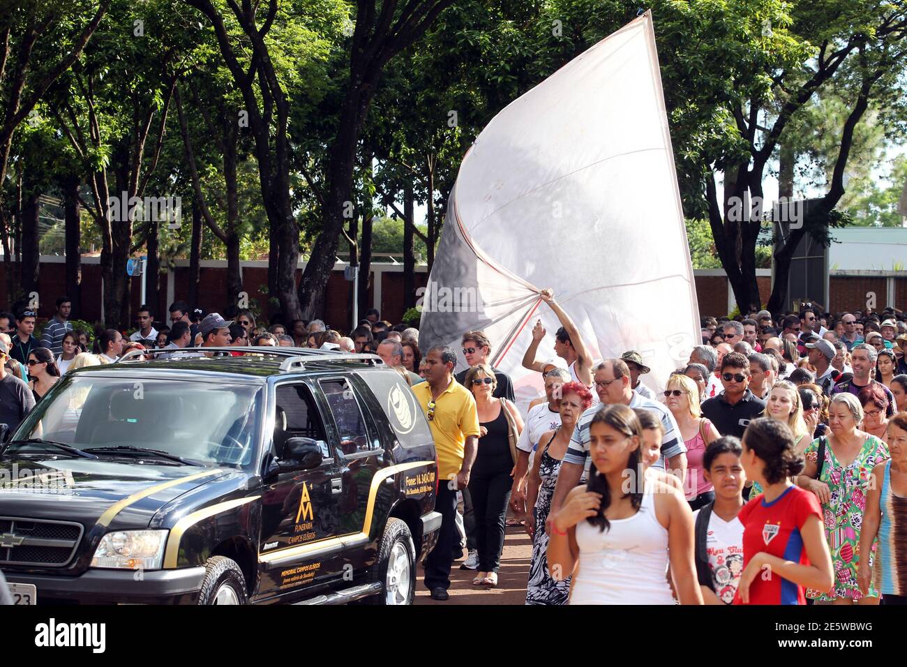 People accompany the car transporting the coffin of Brazil's 1982 World Cup captain Socrates during his funeral procession in Ribeirao Preto December 4, 2011. Socrates, the 'Golden Heel' renowned as one of the great playmakers of his generation, died in hospital on Sunday of septic shock at the age of 57, his doctors said in a statement. REUTERS/Paulo Whitaker (BRAZIL - Tags: SPORT SOCCER OBITUARY) Stock Photo
