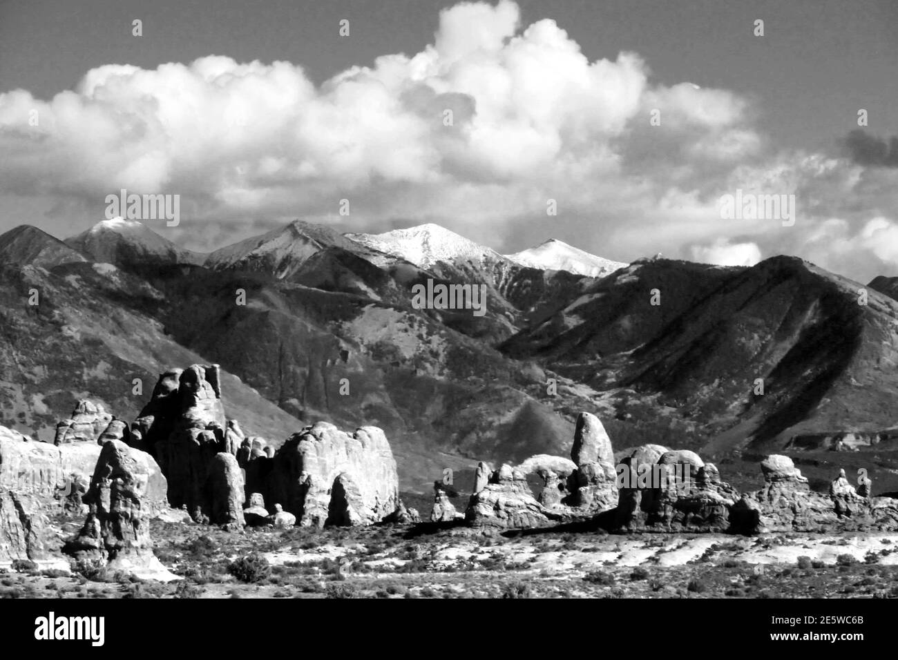 Weathered sandstone fins, towers, spires and Turret Arch with the snow-capped La-Sal Mountains in the background in Black and White Stock Photo