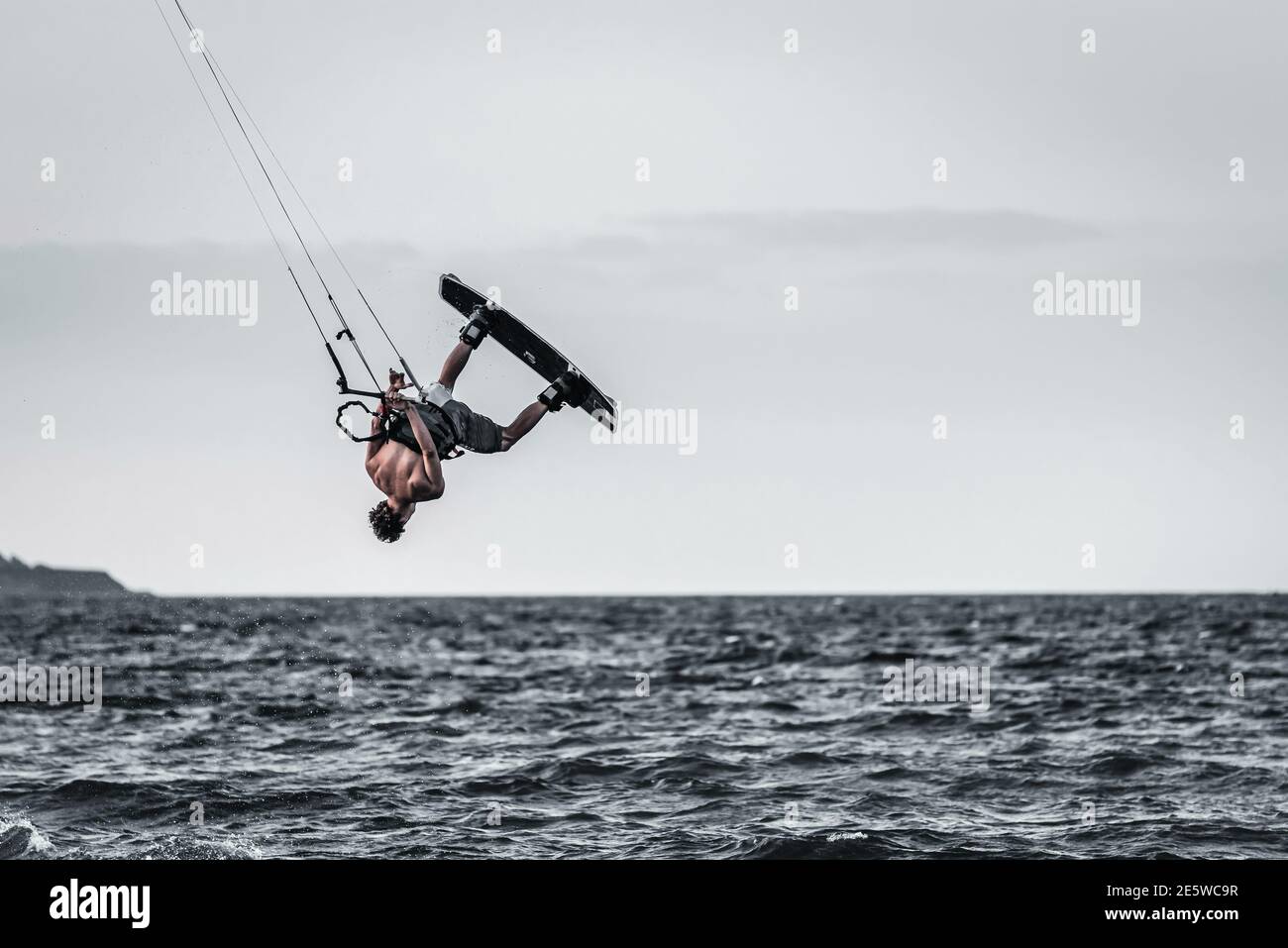 Man kiteboarder performing kitesurfing unhooked tricks, boy kitesurfer jumping kiteboarding