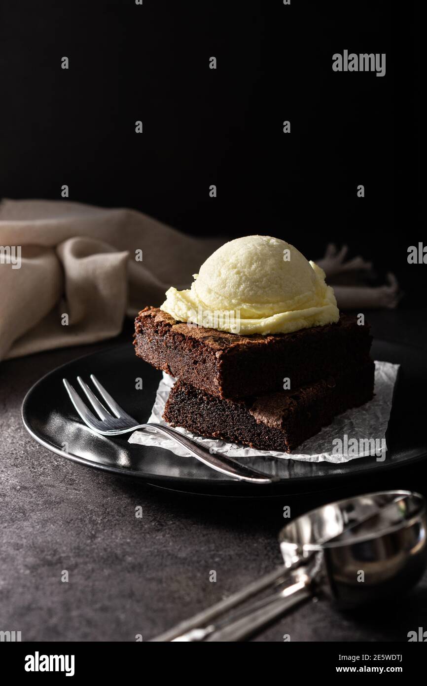 Brownie with vanilla ice cream scoop on black background Stock Photo ...