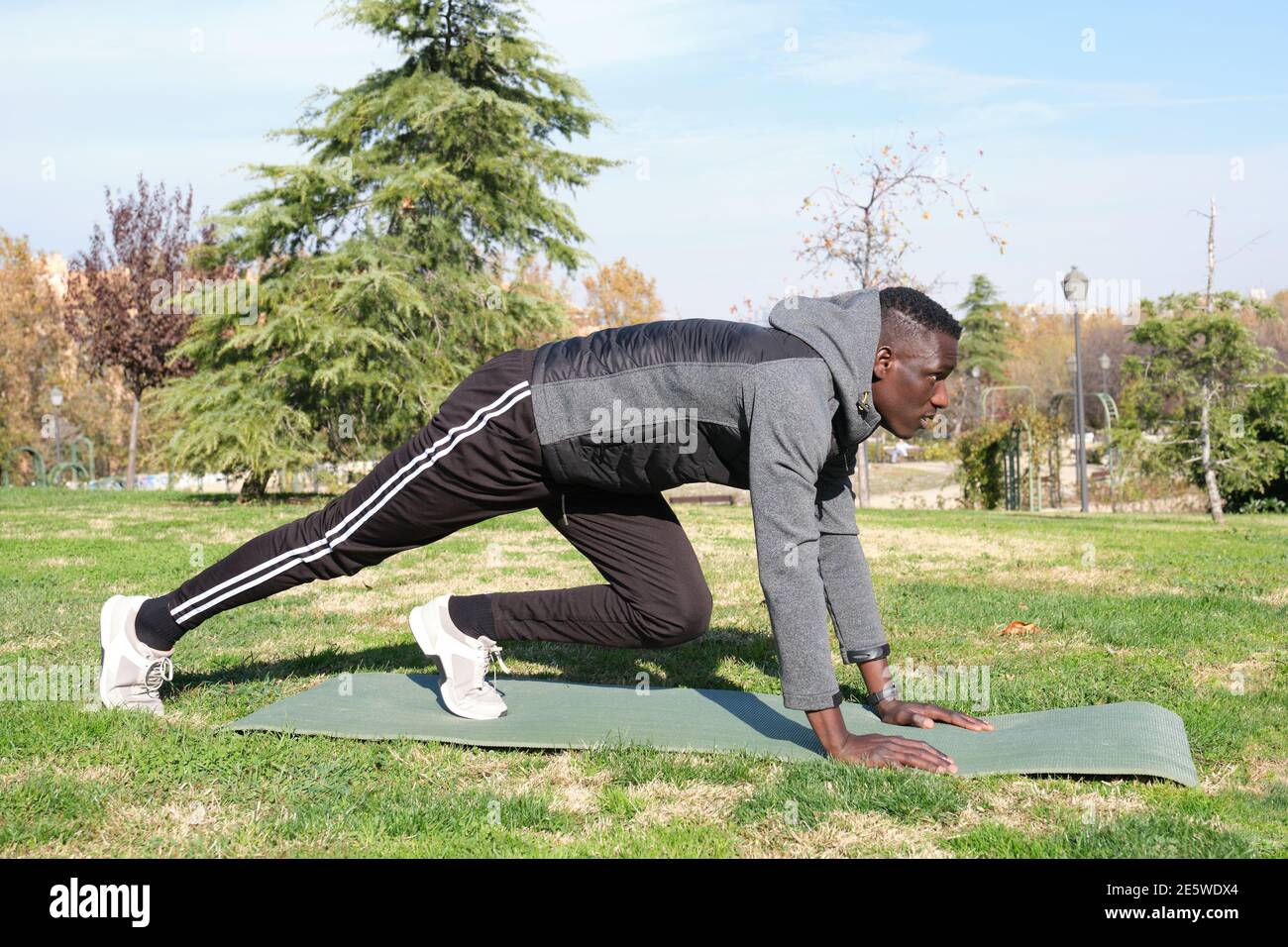 African black man stretching and exercising in a park with a mat ...