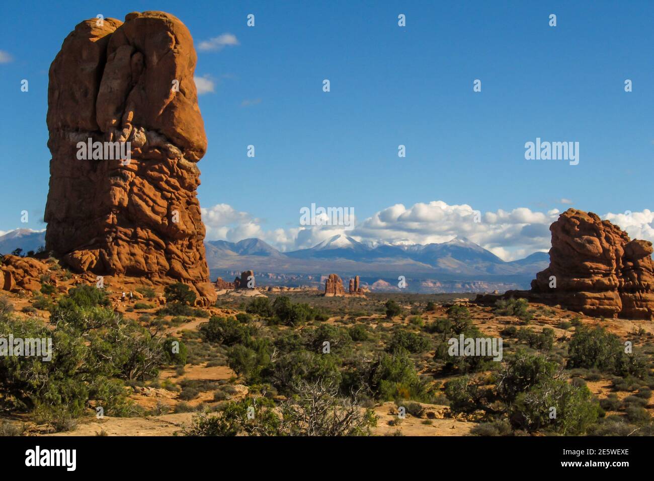Strange towering weathered stone columns in the arid landscape of Archers National Park, Utah, with the snow-capped mountains in the background Stock Photo