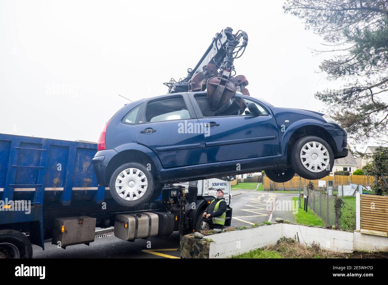 My, private, vehicle,car,a,France,French,made,built, Citroen C3,blue,hatchback,being,removed,by,crane,truck,from,my,driveway,to,be,scrap,scrapped.No,longer,economically,viable,to,maintain,due,to,rust,and,not wanting to throw good money after badge decision, had to be made to destroy vehicle. Failed, MOT. DVLA, Photo taken in seaside resort of Borth,a,few,miles,north,of,Aberystwyth,Ceredigion,Mid,West Wales,Welsh,holiday destination.UK,Europe,mobile,scrapyard,end of life,gone,waste,consumption,throw away,society,recycling,reuse,not,metal,cars,vehicles,crush,grabber,machine,grabbing, Stock Photo