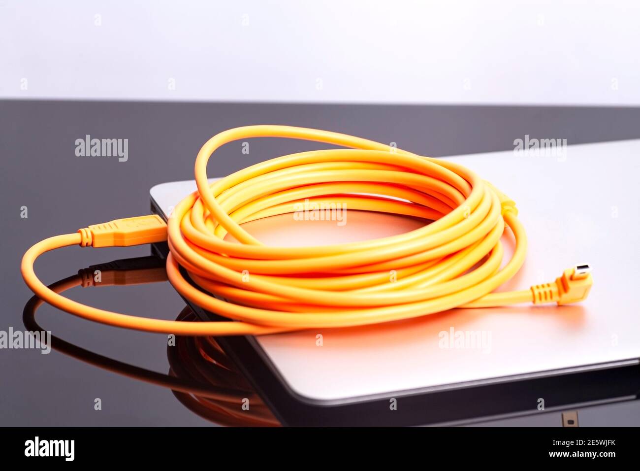 laptop with USB orange rolled cable. Stock Photo