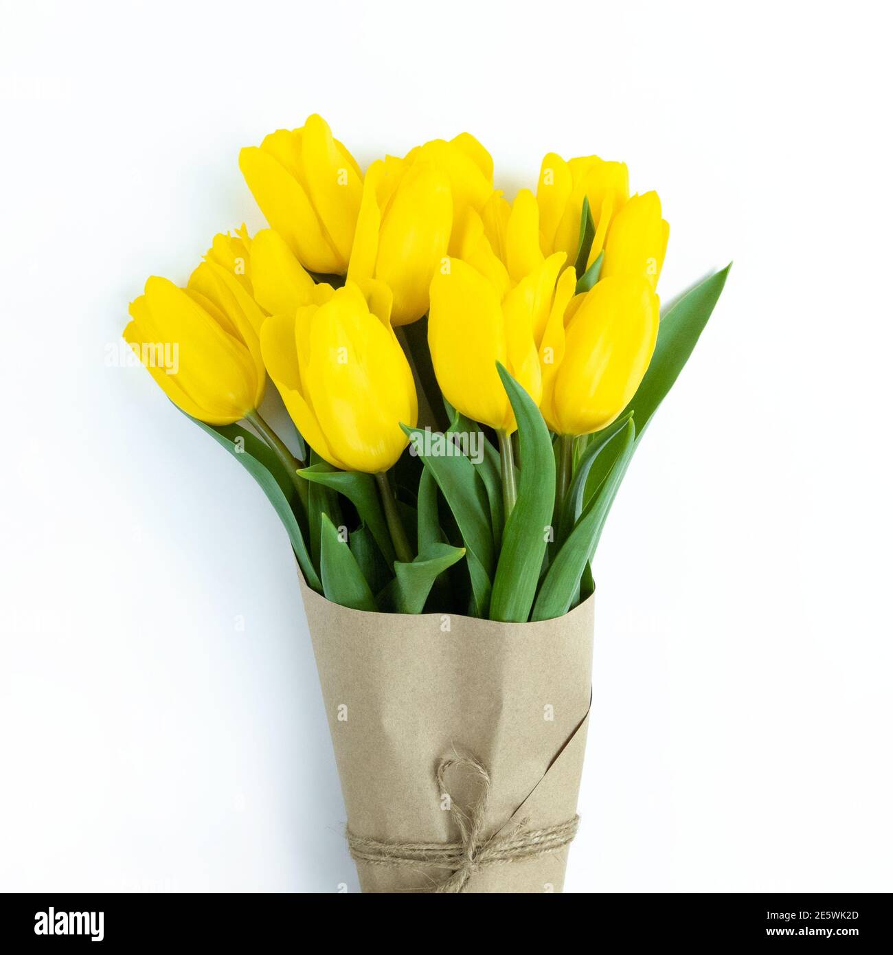 Bouquet of yellow tulips wrapped in craft paper on a white background. Stock Photo