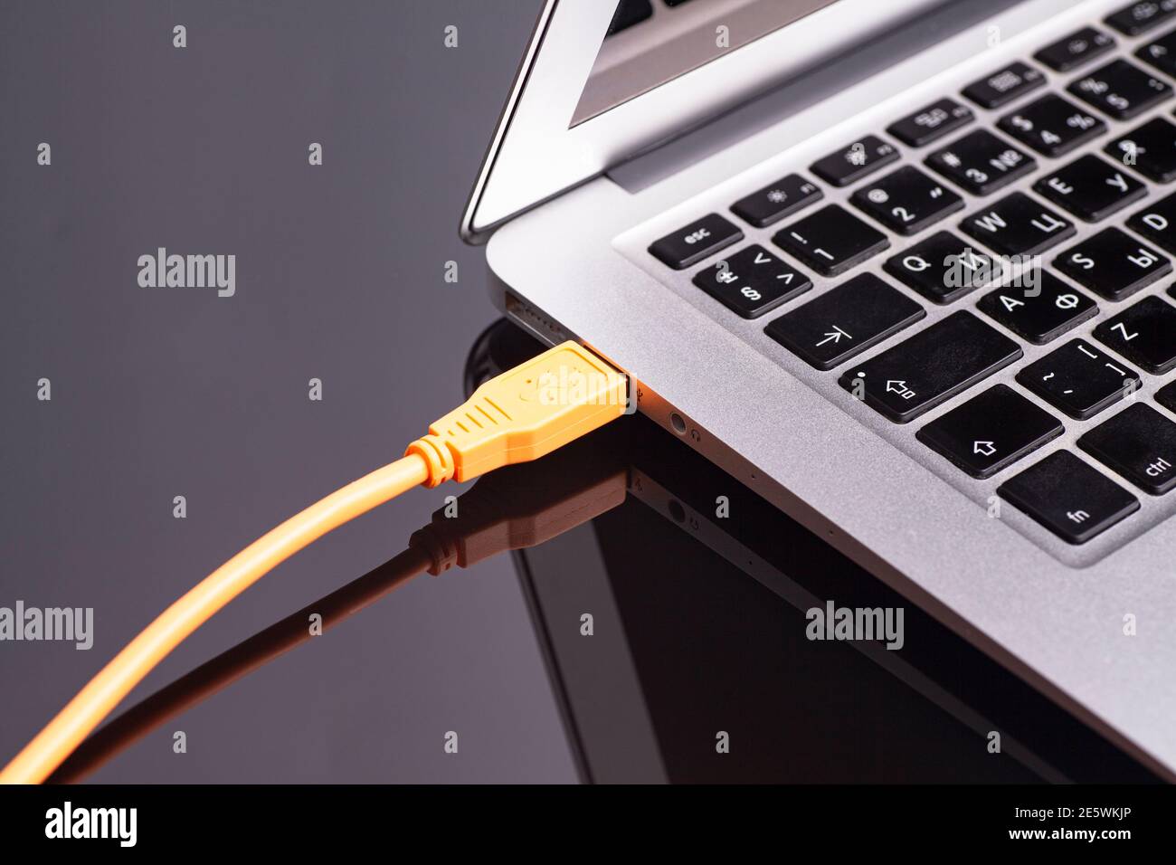 laptop with USB orange cable. Stock Photo