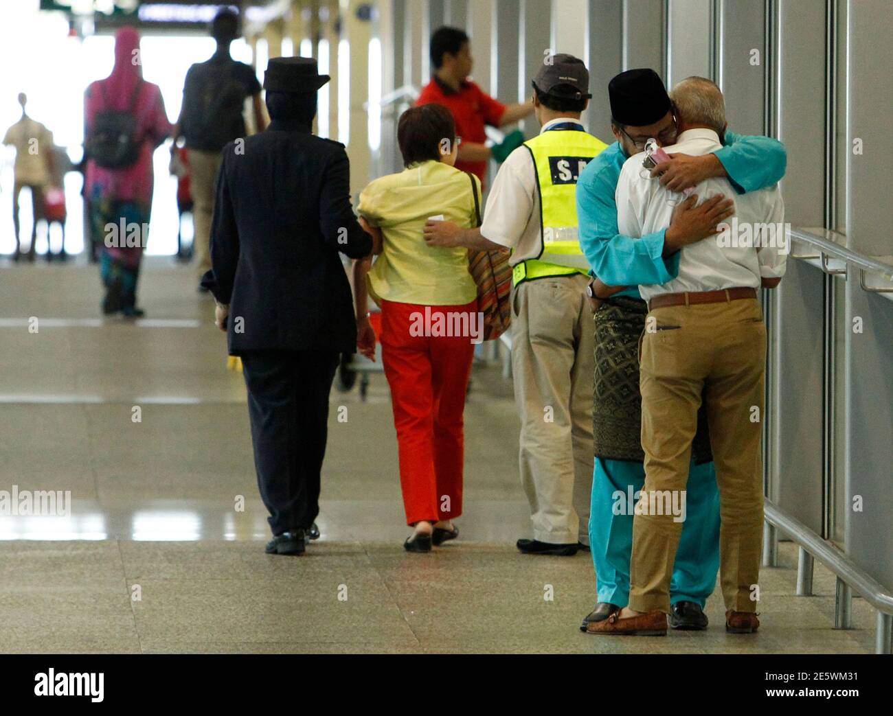 A man (in blue), whose family was onboard Malaysia Airlines MH17, consoles another man who had just arrived with his wife to receive confirmation that their daughter's family was onboard the plane, at Kuala Lumpur International Airport in Sepang July 18, 2014. The United States believes a surface-to-air missile brought down a Malaysian airliner that crashed in eastern Ukraine on Thursday, killing all 298 people on board, an incident that sharply raises the stakes in a conflict between Kiev and pro-Moscow rebels.  REUTERS/Edgar Su (MALAYSIA - Tags: TRANSPORT DISASTER) Stock Photo