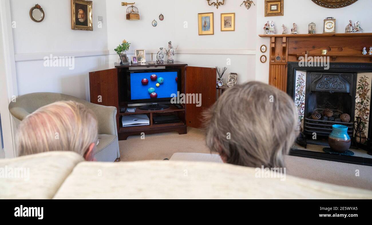 Elderly couple in their 80s watching bowls on television in their sitting room during lockdown   Photograph taken by Simon Dack Stock Photo