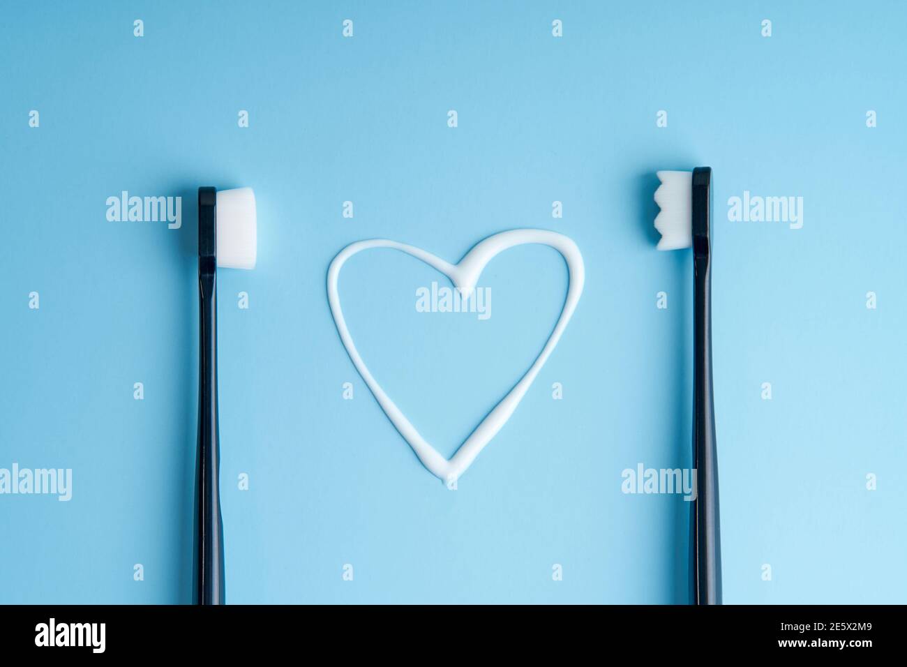 Heart shaped toothpaste between two toothbrushes. Stock Photo