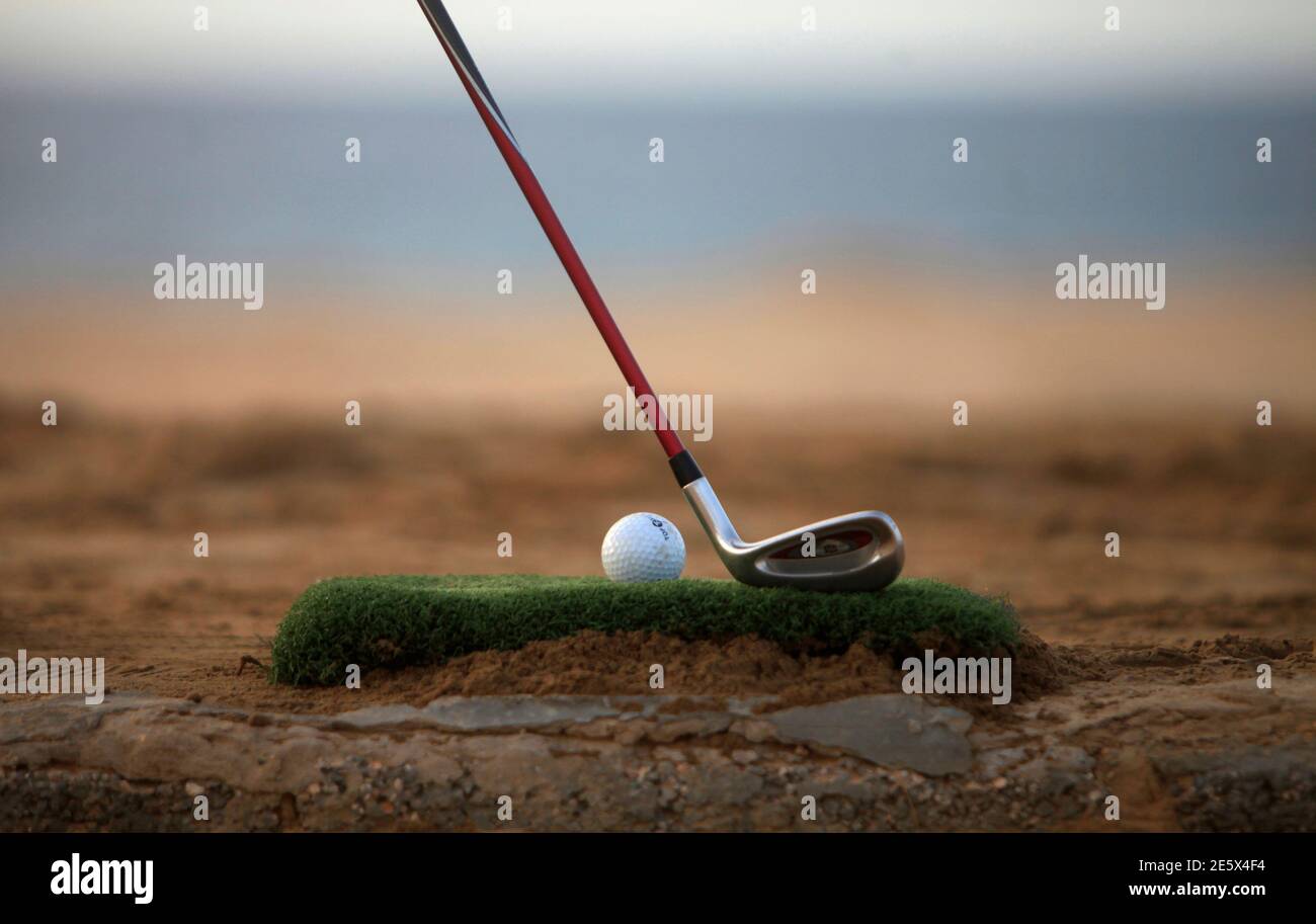 A golf club is positioned near a ball as a boy plays a game near the beach  in Gargaresh area in Tripoli September 17, 2013. Among the rubbish-strewn  bushes and occasional bullet