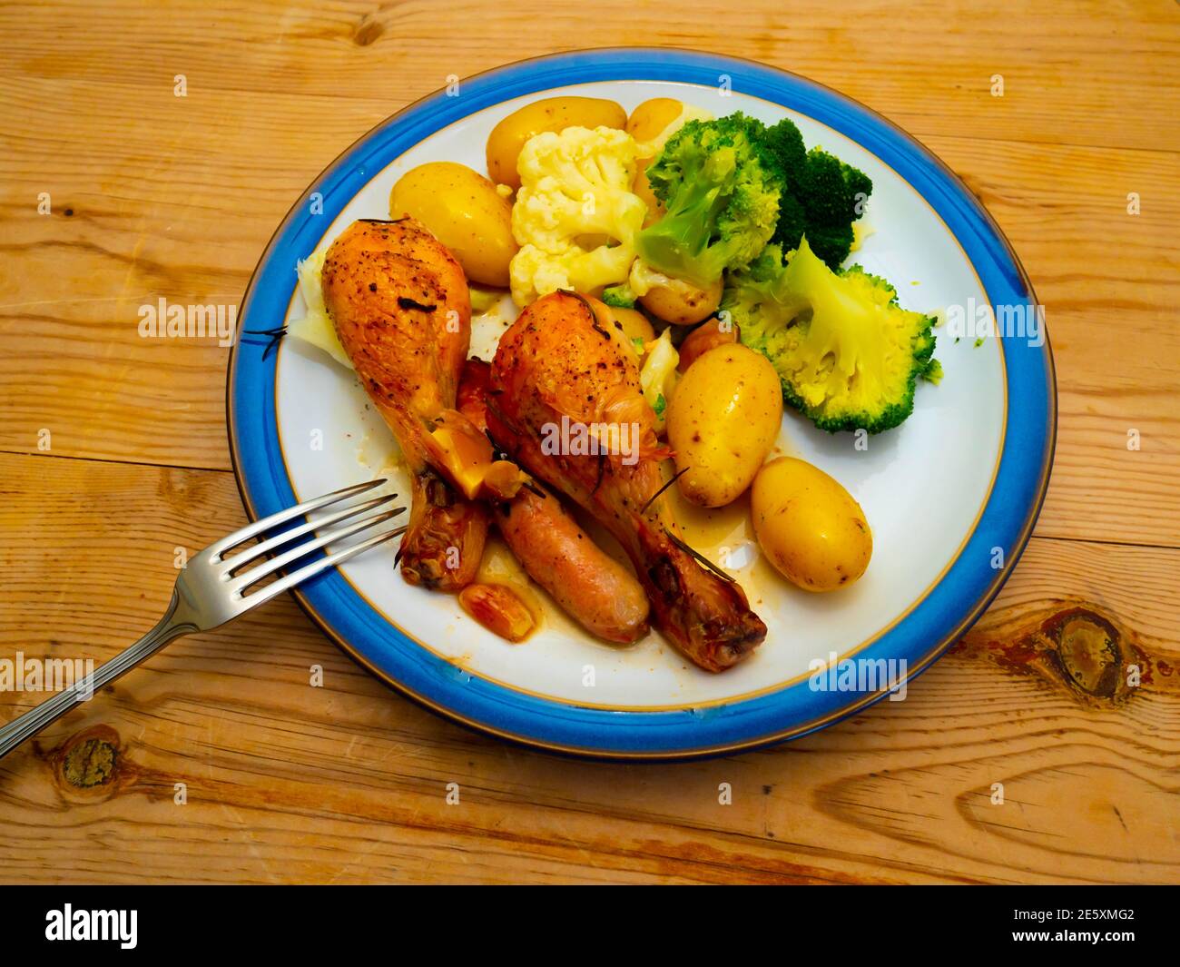 Decompose Blot persecution Lunch main course chicken drumsticks with sausages broccoli cauliflower and  new potatoes on a white plate blue edge wooden table top with cutlery Stock  Photo - Alamy
